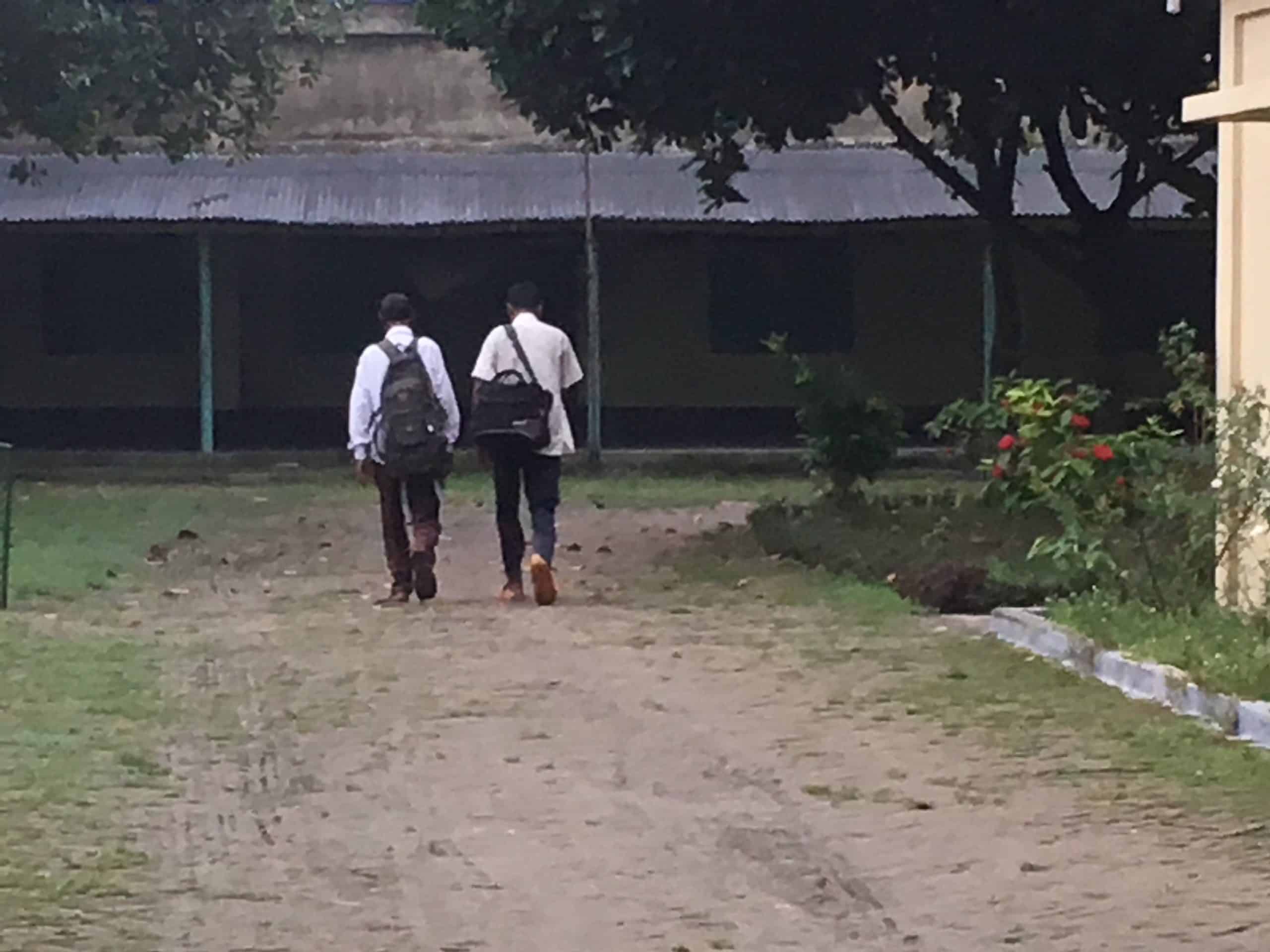 two men wearing backpacks walking to a building where Hands to the Plow training is